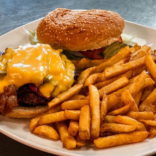 Cheeseburger with melted cheese, bacon, and caramelized onions, served with a side of golden french fries.